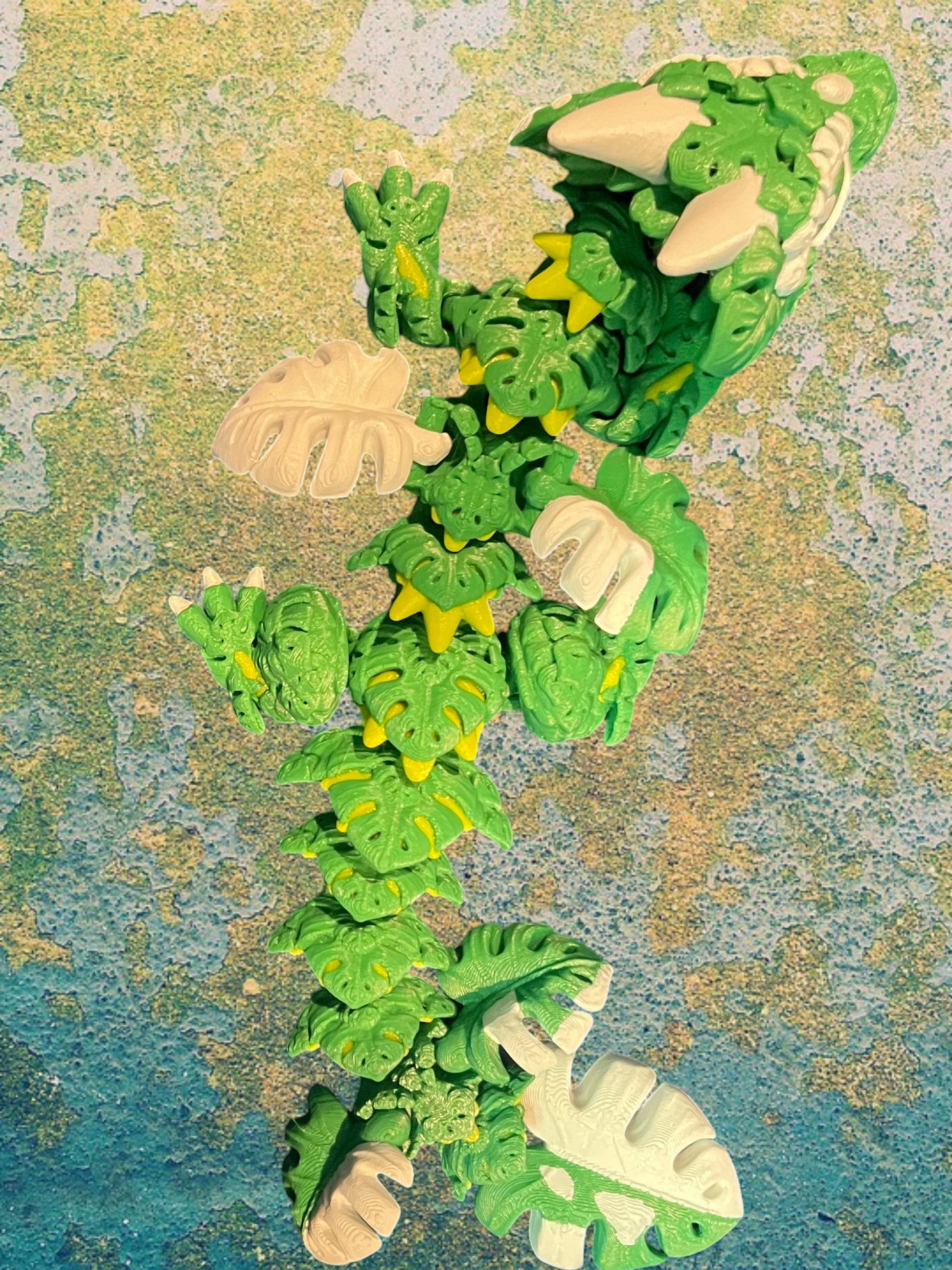 1 Layer At A time Baby Monstera Plant Dragon, a green and white articulated dragon with monstera leaf details and yellow accents.