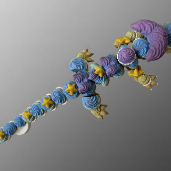 1 Layer At A time articulated 3D printed dragon toy with cupcake frosting texture, blue, purple, yellow, and green colors, and yellow stars.