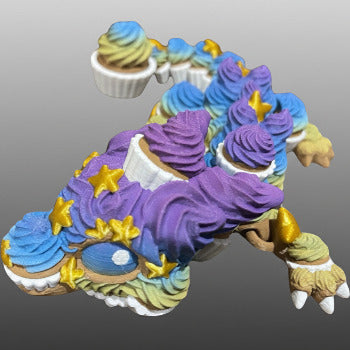 1 Layer At A time 3D printed cupcake dragon with purple, blue, and yellow frosting details and gold stars.